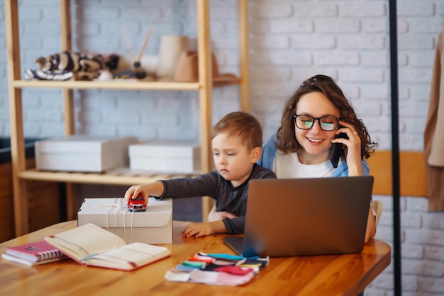 La giovane madre lavora con il ragazzino Donna d'affari che parla al telefono e discute di problemi di lavoro