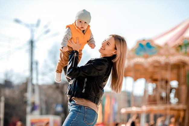 La giovane mamma alla moda cammina con il bambino nel parco. Mamma felice