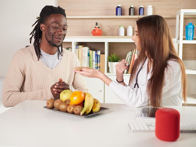 La giovane nutrizionista femminile in ufficio suggerisce di mangiare lo zenzero al suo paziente