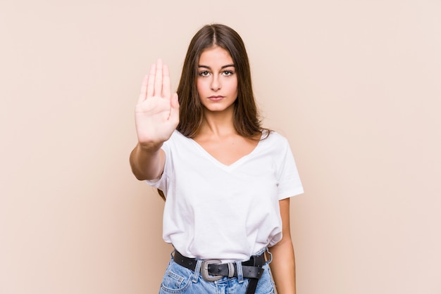 La giovane posa caucasica della donna ha isolato la condizione con il fanale di arresto di rappresentazione della mano tesa, impedendovi.