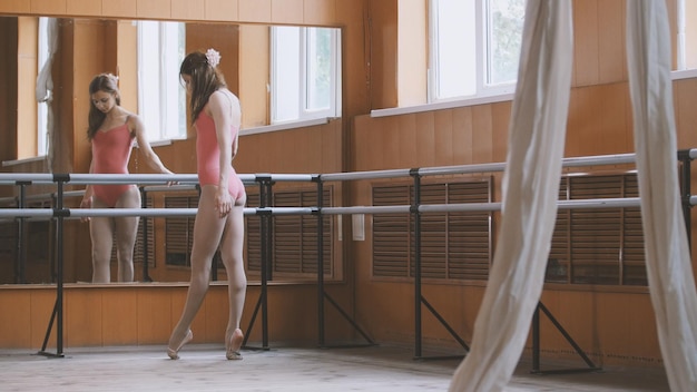 La giovane ragazza acrobatica mostra la flessibilità del corpo al bar del balletto, artista del circo