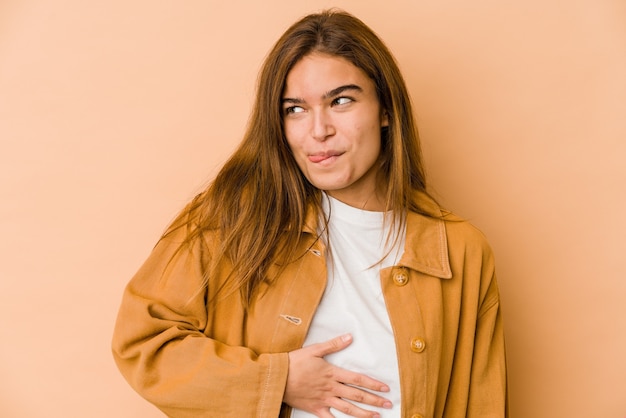 La giovane ragazza adolescente caucasica magra tocca la pancia, sorride delicatamente, mangia e concetto di soddisfazione.