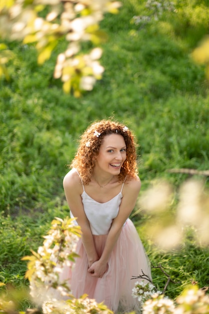 La giovane ragazza attraente cammina nel parco verde di primavera che gode della natura di fioritura