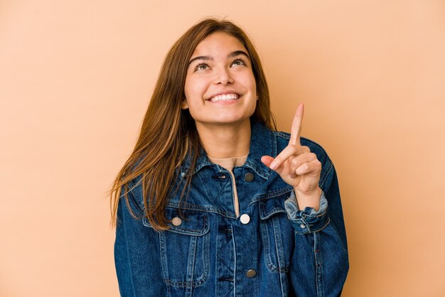 La giovane ragazza caucasica magra dell'adolescente indica con entrambe le dita anteriori in su mostrando uno spazio vuoto.