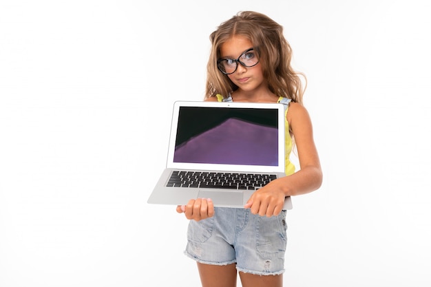La giovane ragazza caucasica sta con il computer portatile