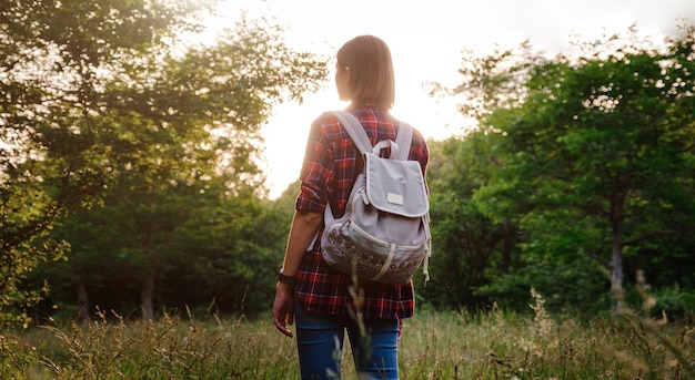 La giovane ragazza dei pantaloni a vita bassa si gode il tramonto Donna di viaggio con lo zaino