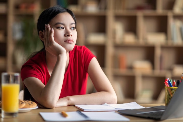 La giovane ragazza giapponese stanca e annoiata ascolta la lezione online all'interno della stanza Stanchezza di lavoro eccessivo e problemi con lo studio