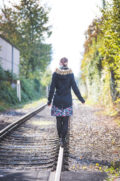 La giovane ragazza graziosa sta equilibrando sul concetto della ferrovia per viaggiare