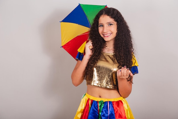La giovane ragazza teenager brasiliana con frevo copre il carnevale con l'ombrello che invita con le mani