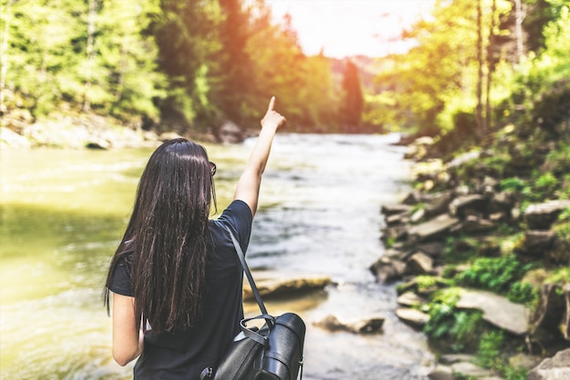 La giovane ragazza turistica gode della natura vicino al fiume della montagna