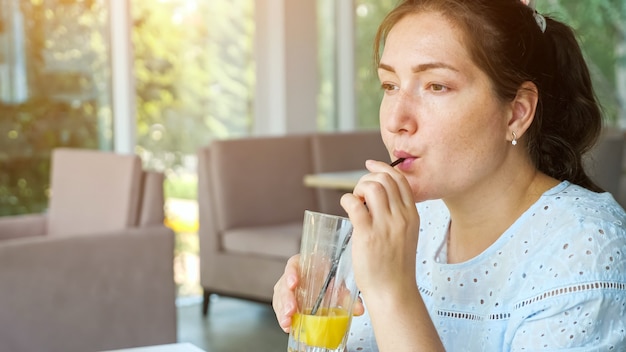 La giovane signora attraente beve il succo in caffè