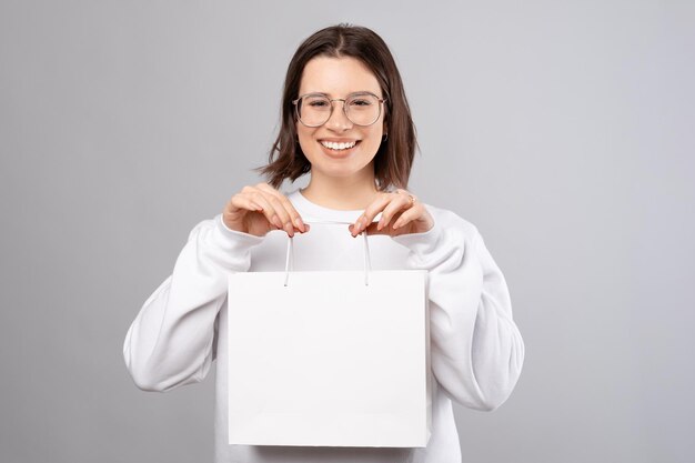 La giovane signora sta tenendo una borsa della spesa bianca con lo spazio della copia