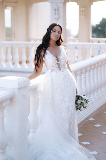 La giovane sposa lussuosa in un guardaroba alla moda costoso posa per un servizio fotografico di matrimonio in una località turistica di lusso