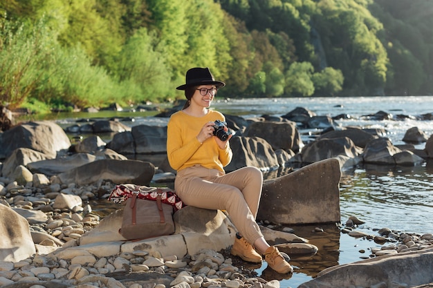 La giovane viaggiatrice sta scattando foto della natura con una fotocamera retrò