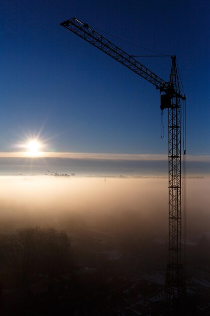 La gru da costruzione nella nebbia all'alba