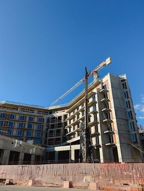 La gru da costruzione si trova dietro una recinzione vicino a un edificio a più piani