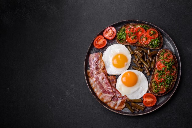 La gustosa colazione consiste in uova, pancetta, fagioli, pomodori con spezie ed erbe aromatiche