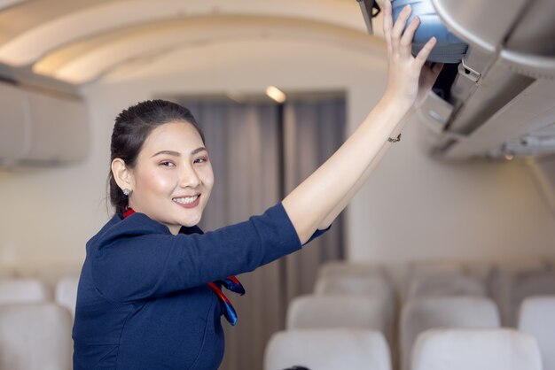 La hostess aiuta i passeggeri a mettere i bagagli nella cabina dell'aereo. Hostess in aereo.