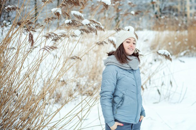 La lancio felice della giovane donna nevica su in aria nel giorno di inverno soleggiato