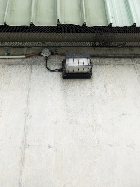 La lanterna d'epoca con la griglia metallica di sicurezza per il sistema di sicurezza sulla parete della fabbrica vista frontale con lo spazio di copia