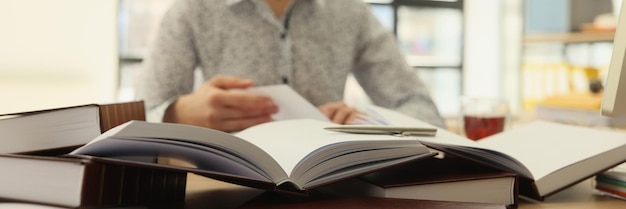 La lavoratrice legge libri per trovare informazioni per la ricerca professionale concentrata sulla donna