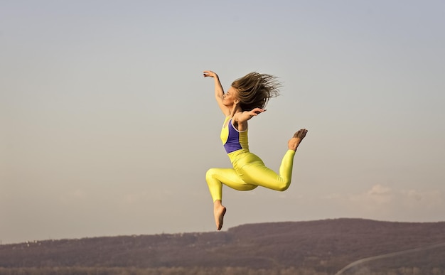 La libertà è lo sport della vita in movimento pieno di energia Attraente giovane donna sportiva si allena nella palestra all'aperto esercizio mattutino ginnasta nazionale ucraina Acrobazie e ginnastica ragazza che salta in alto