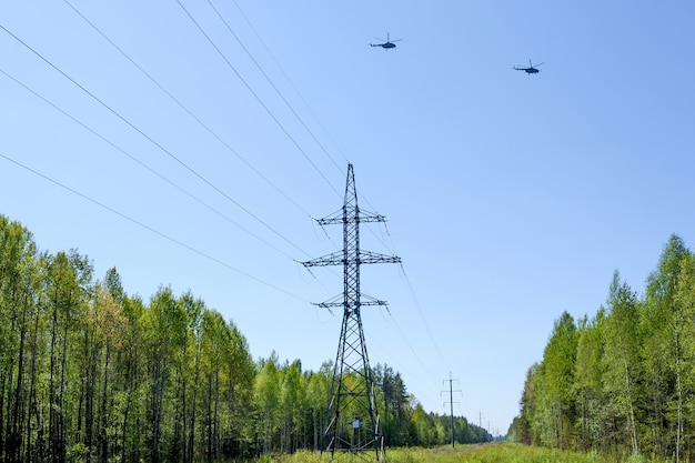 La linea di trasmissione di energia ad alta tensione passa attraverso la foresta. elicotteri che volano nel cielo