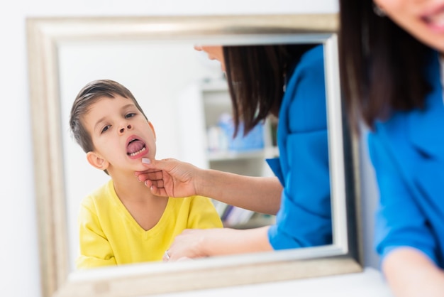 La logopedista corregge i difetti del linguaggio in un bambino nel suo ufficio