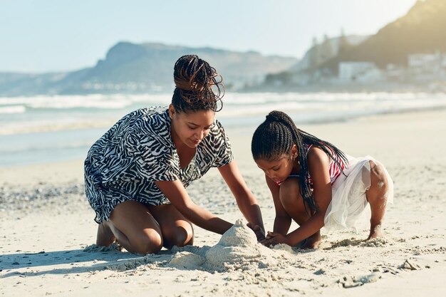 È la loro attività preferita in spiaggia Foto di una madre e la sua piccola figlia che costruiscono insieme un castello di sabbia sulla spiaggia