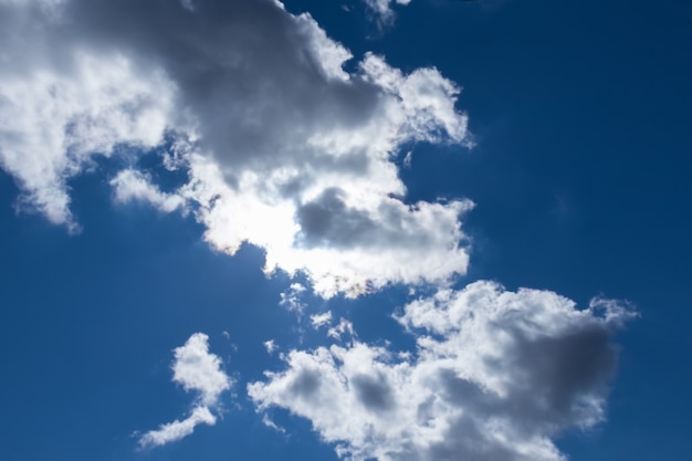 La luce del sole splende attraverso le nuvole grigio-bianche sul cielo blu scuro