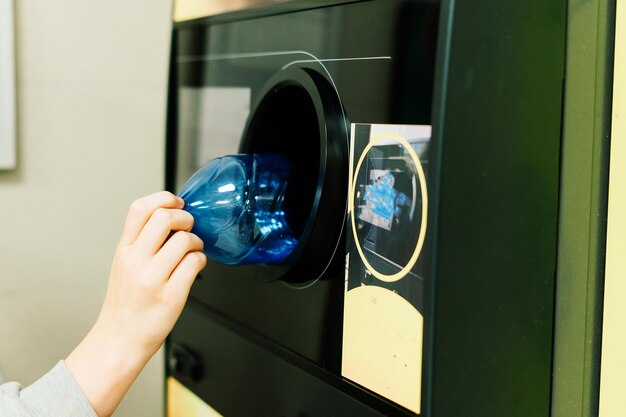 La macchina di riciclaggio inversa che distribuisce i contanti l'uomo mette a mano una bottiglia di plastica nella macchina