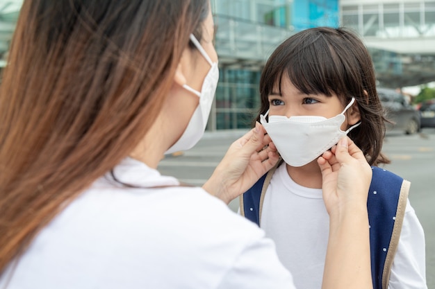 la madre aiuta sua figlia a indossare una maschera medica per proteggere l'epidemia di Covid19