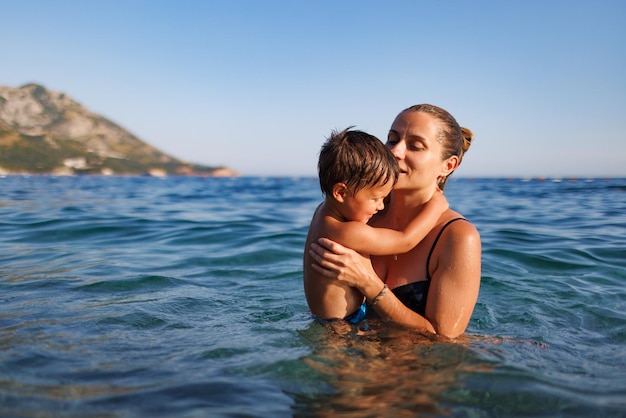 La madre allegra gioca con suo figlio nel mare