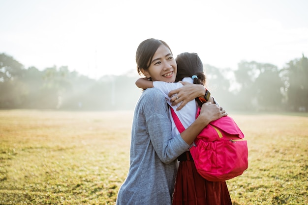 La madre asiatica abbraccia e abbraccia sua figlia che va a scuola