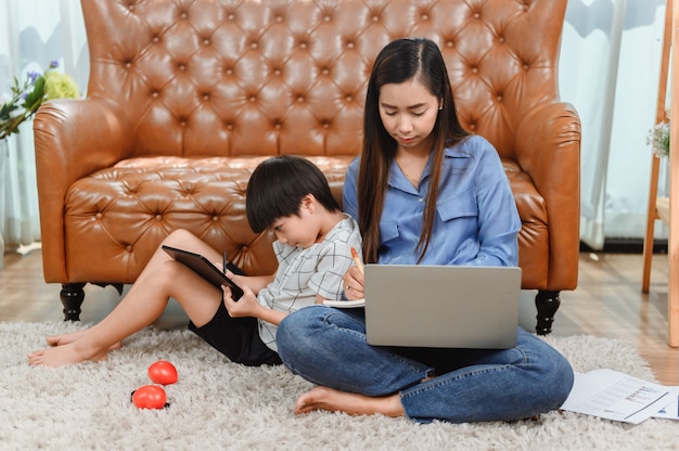La madre asiatica lavora a casa. Mamma insieme al figlio. Istruzione di apprendimento online per bambini. Nuovo stile di vita normale e attività familiare.