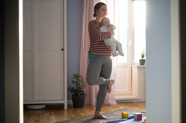 La madre con il bambino fa yoga a casa per essere forte e in salute