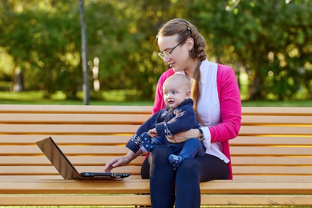 La madre con il bambino lavora usando il laptop all'aperto