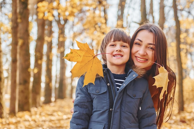 La madre con suo figlio si diverte all'aperto nella foresta autunnale