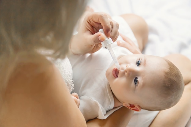 La madre dà la medicina al bambino per le coliche. Messa a fuoco selettiva. Persone.