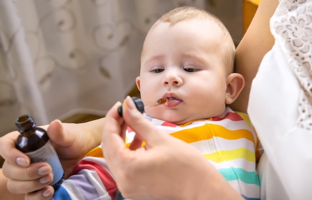 La madre dà la medicina per le coliche al piccolo bambino Messa a fuoco selettiva