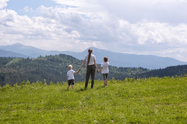 La madre e due piccoli figli stanno tenendosi per mano su un campo verde