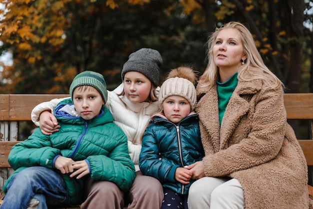 La madre e i bambini della famiglia felice sono nel parco cittadino d'autunno Essi posano sorridendo giocando e divertendosi Alberi gialli luminosi