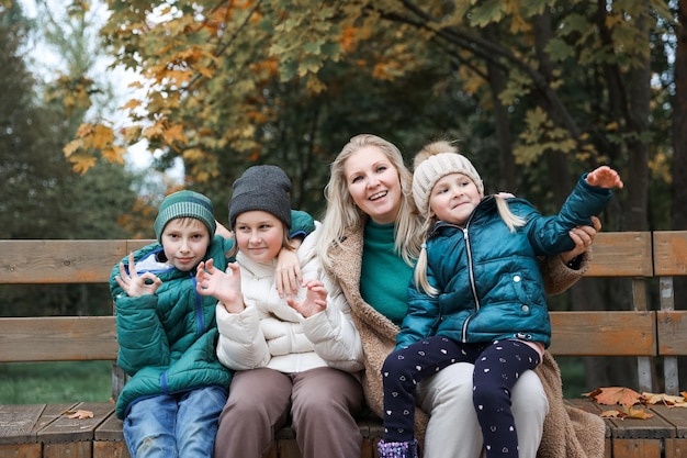 La madre e i bambini della famiglia felice sono nel parco cittadino d'autunno Essi posano sorridendo giocando e divertendosi Alberi gialli luminosi