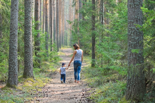 La madre e il bambino camminano sulla strada rurale del paese nell&#39;abetaia