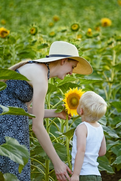 La madre e il figlio stanno in piedi e inalano il profumo del girasole