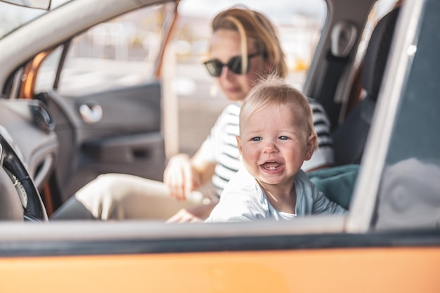 La madre e il suo neonato durante un viaggio estivo con la famiglia seduti sul sedile anteriore del papà in attesa in macchina che il padre compri i biglietti per la farry