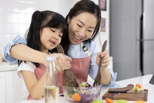 La madre e la bambina stanno preparando l'insalata in una ciotola