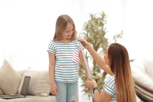 La madre e la figlia attente effettuano misurazioni per i vestiti nuovi il concetto di genitorialità