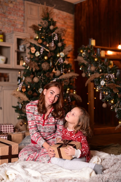 La madre e la figlia che si siedono sul pavimento vicino all'albero di Natale