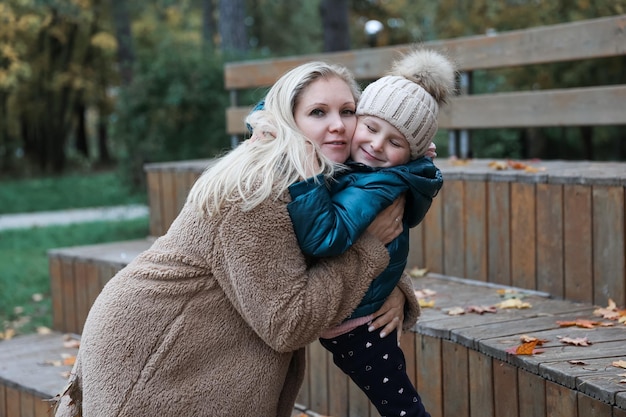 La madre e la figlia della famiglia felice sono nel parco cittadino d'autunno Posano sorridendo giocando e divertendosi Alberi gialli luminosi